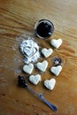 Raspberry marmalade in bowl, a spoon with marmalade and dough in hearts shapes